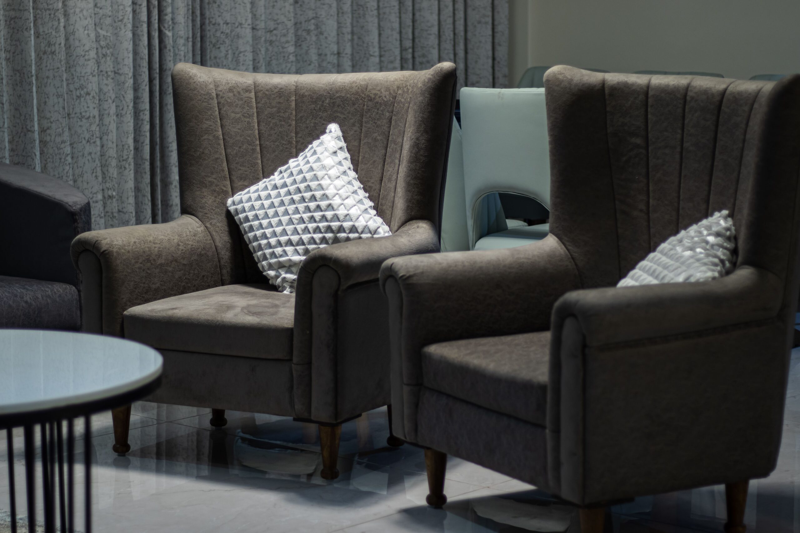Two brown armchairs with decorative pillows in a cozy, stylish interior.