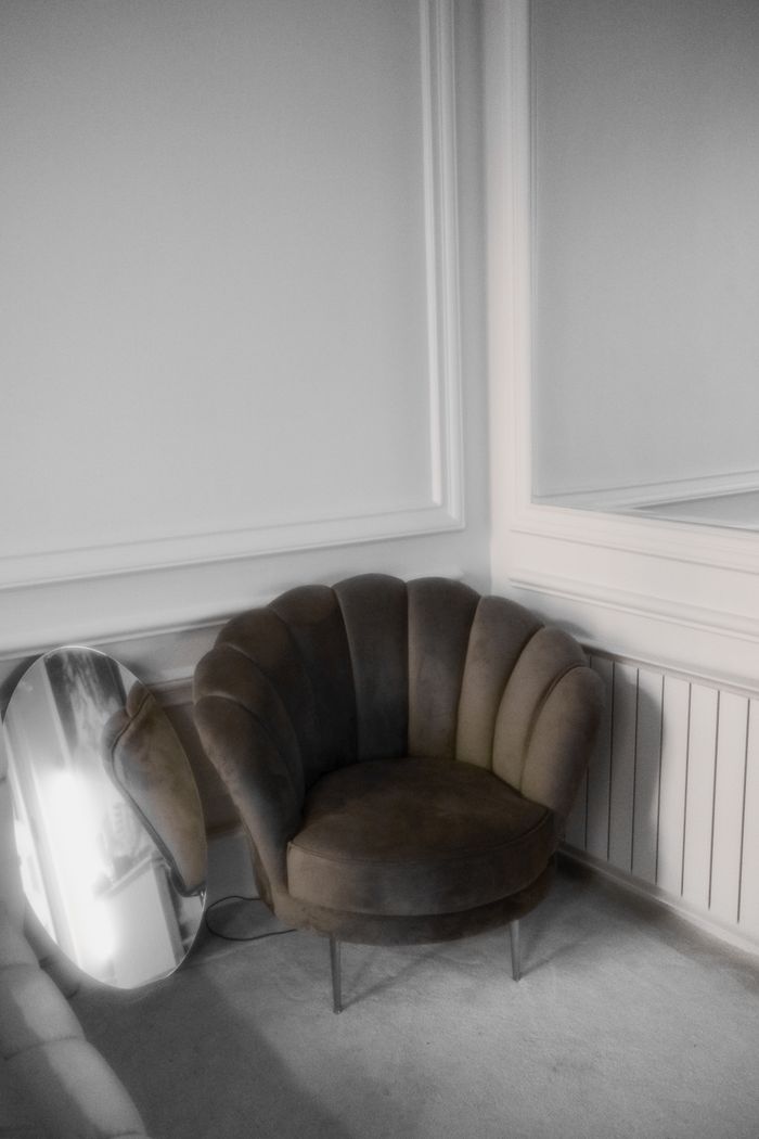 A stylish velvet chair with metal legs in a modern minimalist interior setting.