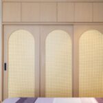 Home Contemporary bedroom with wooden wardrobe and mirror, emphasizing minimalist design.