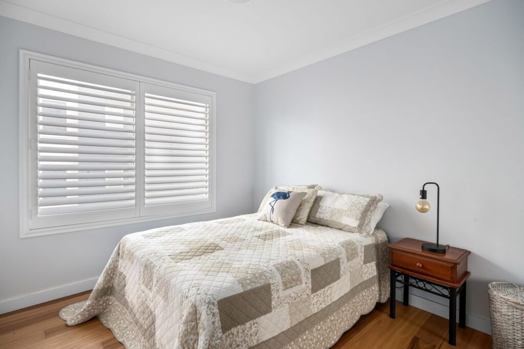 A minimalist bedroom featuring a quilted bedspread, nightstand, and soft lighting for ultimate comfort.