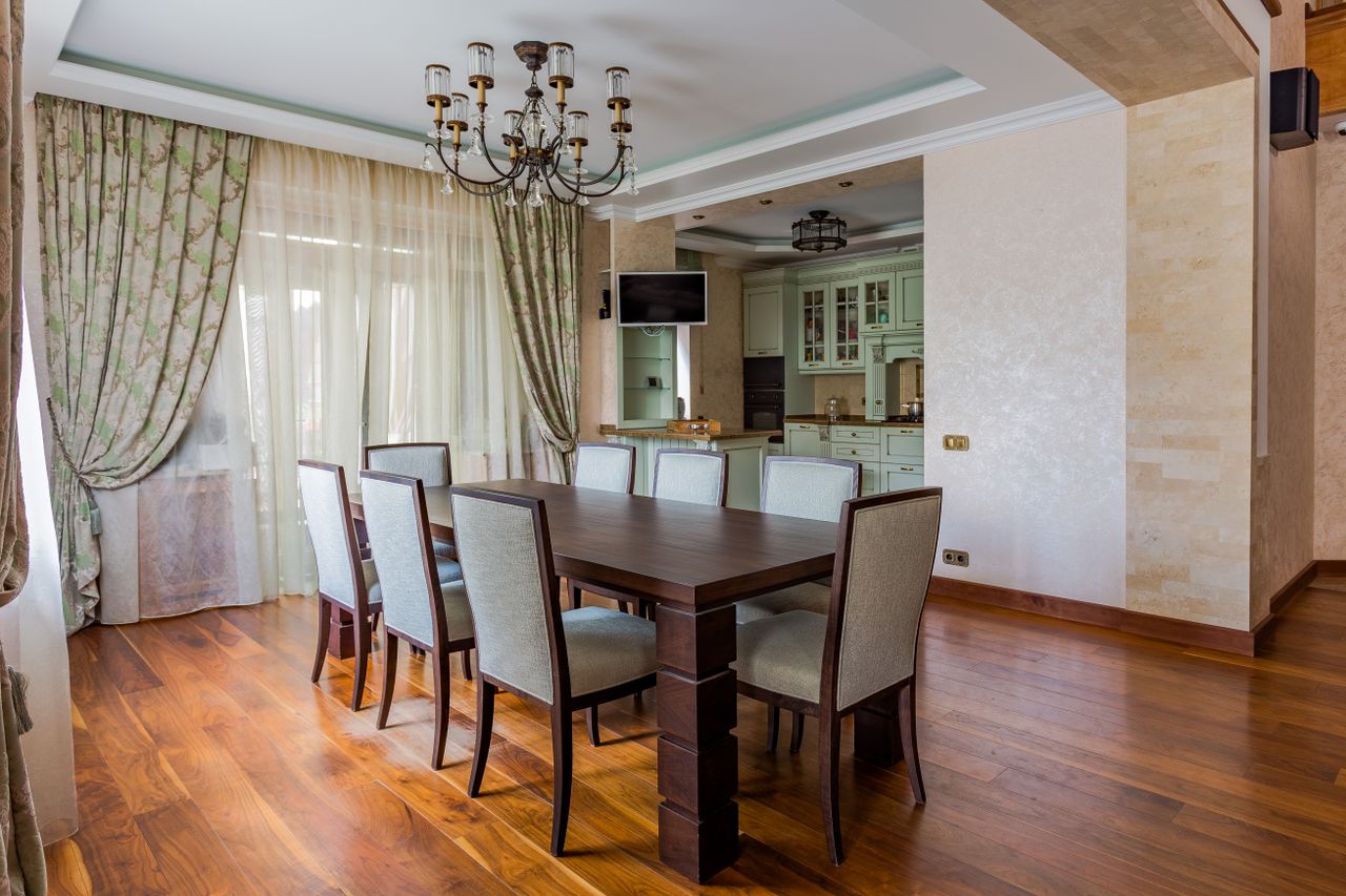 Spacious dining room with a dark wooden table, elegant chairs, and ambient lighting.