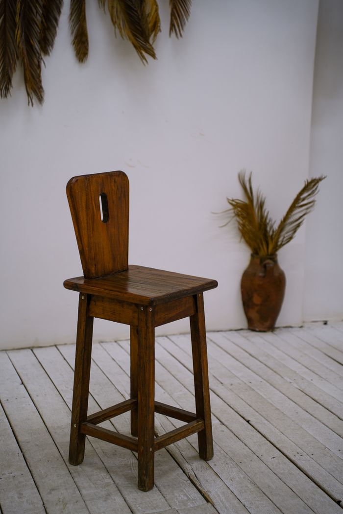 A rustic wooden chair placed in a minimalist setting with decorative natural elements.