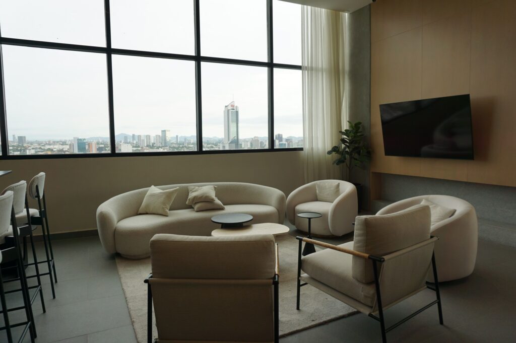Contemporary living room with city skyline, featuring stylish furniture and large windows.