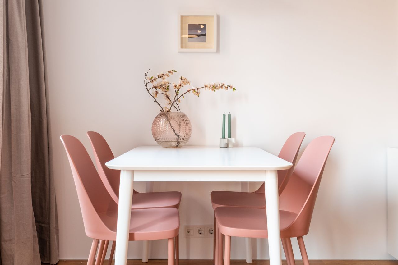 Pink chairs placed near table decorated with branches of gentle sakura in blossom and candles