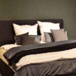 Home Creative design of bed with collection of cushions and cover between lamps in house