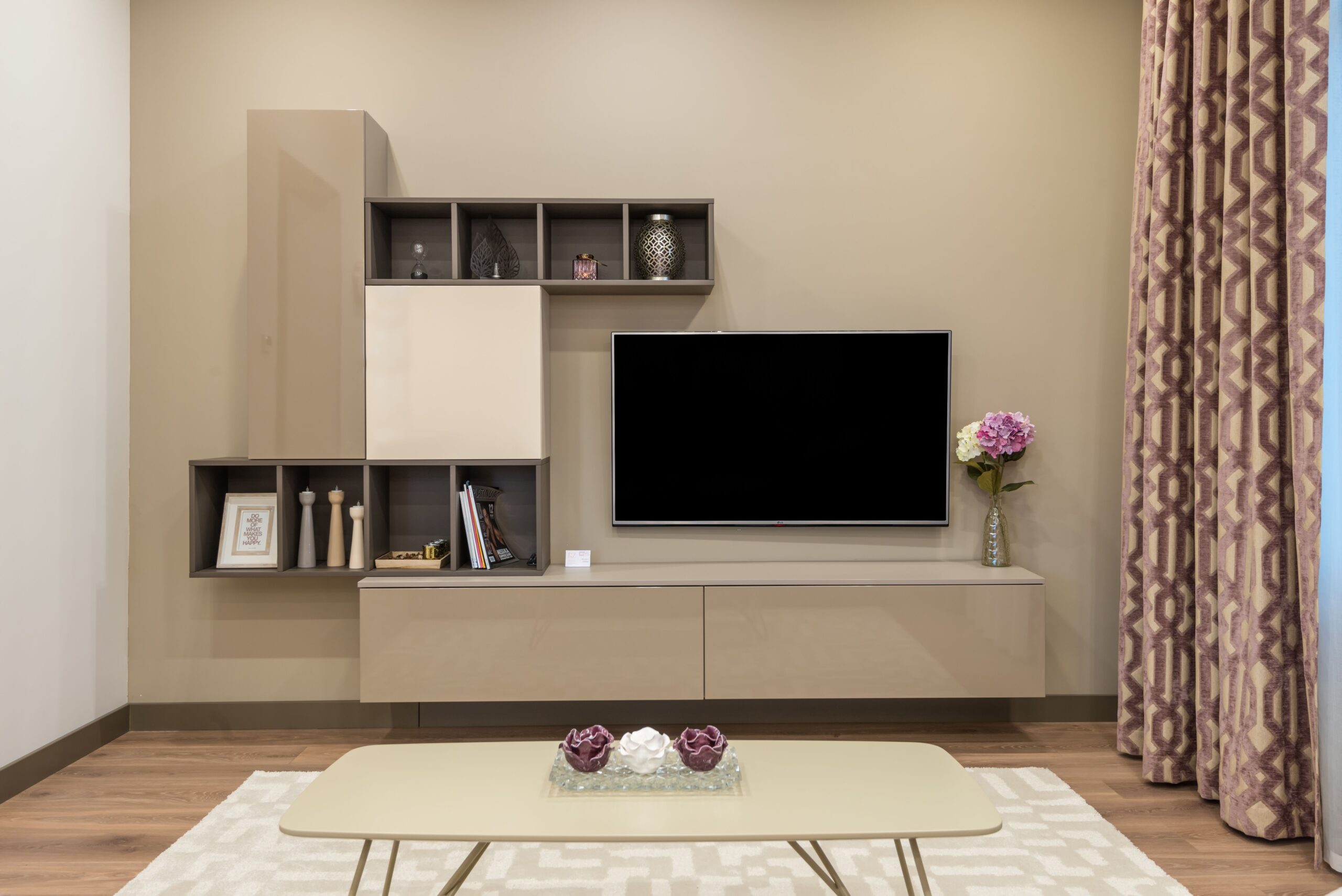 Home Coffee table placed on carpet near modern TV set and minimalist cabinet decorated with vase of flowers in living room