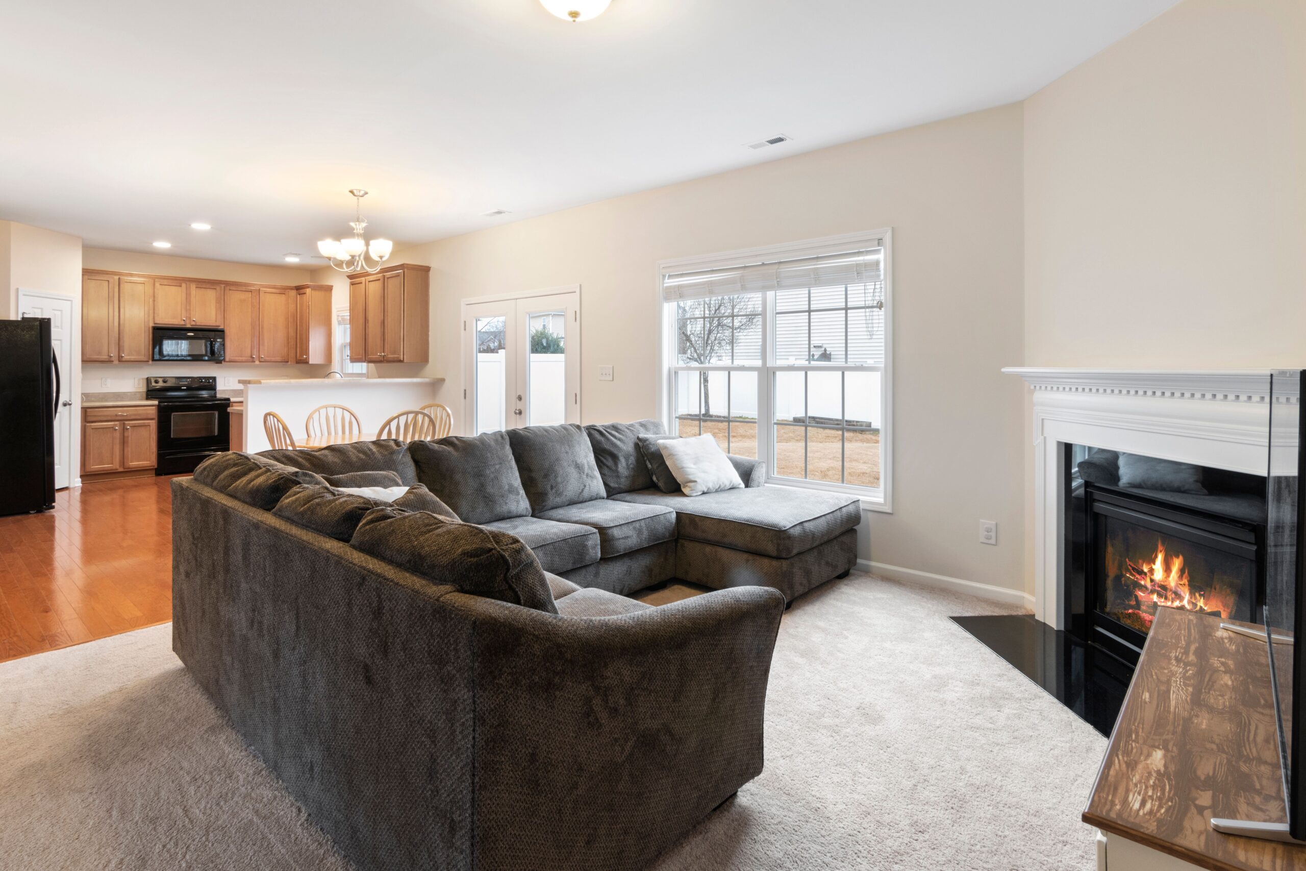 Home Modern living room with cozy sofa, fireplace, and open kitchen layout. Ideal for family gatherings.