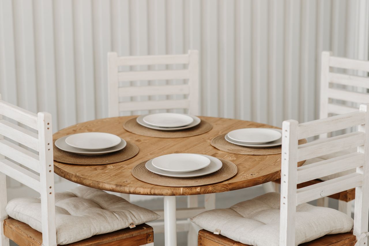Cozy dining setup with wooden table, ceramic plates, and cushioned chairs in a minimalist style.