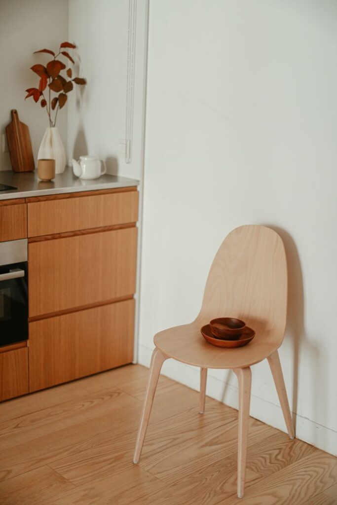 Minimalist kitchen corner with wooden chair and decor items, showcasing simple and modern design.