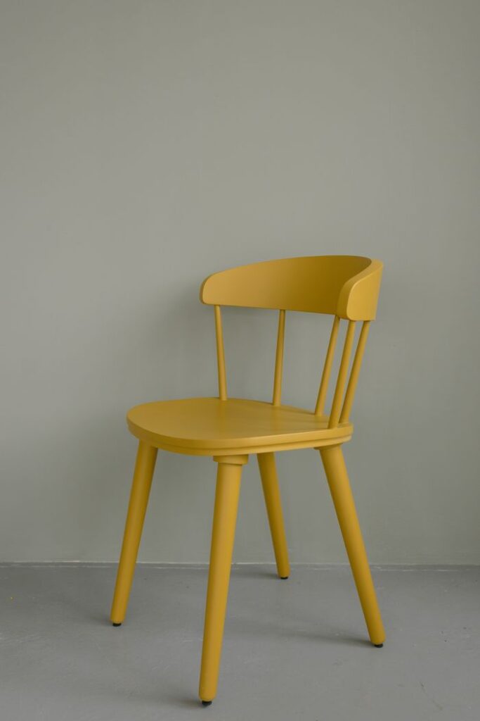 Minimalistic yellow wooden chair on a gray background, ideal for interior design.
