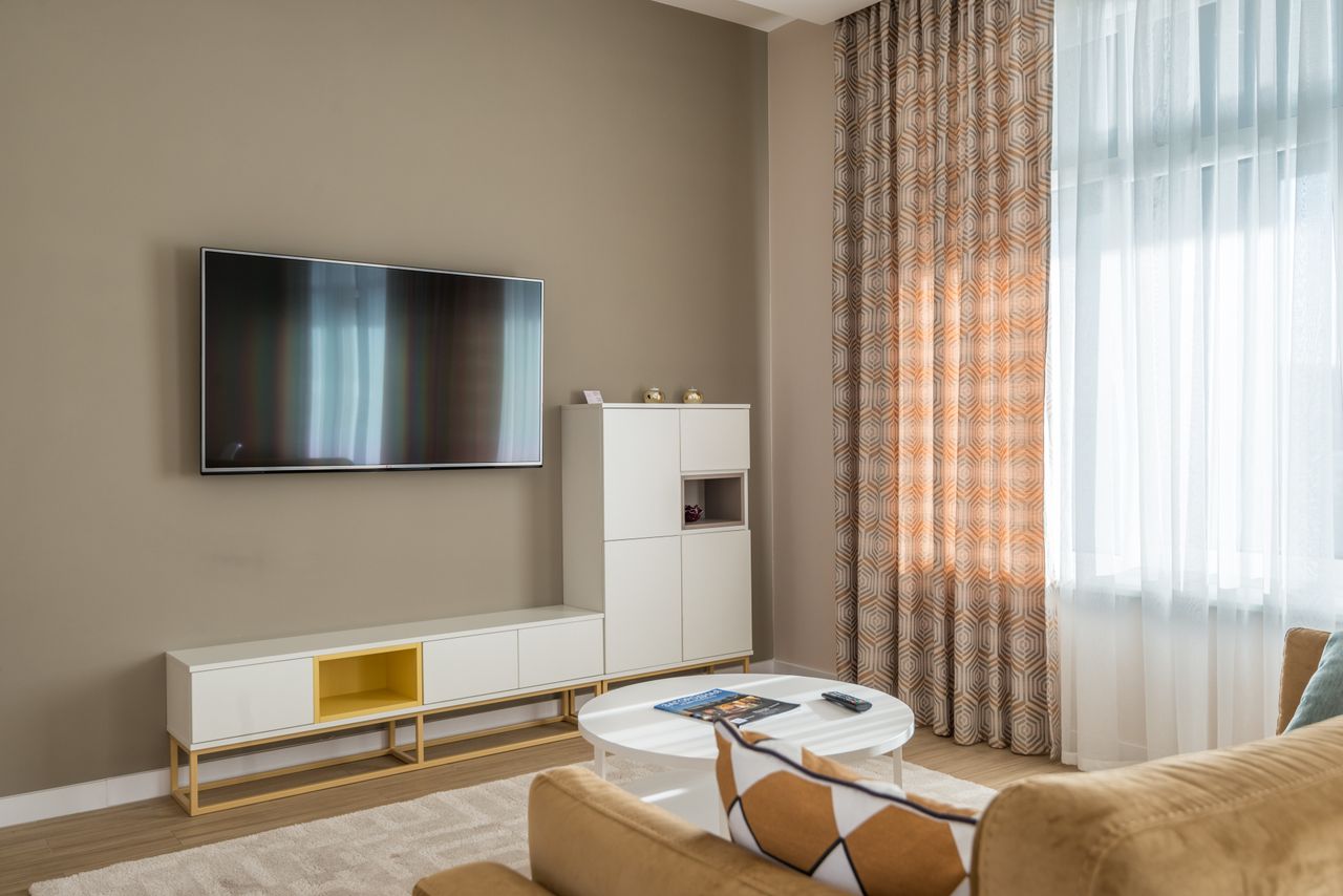 Tv unit Cozy living room interior with beige walls, flat-screen TV, and stylish decor.