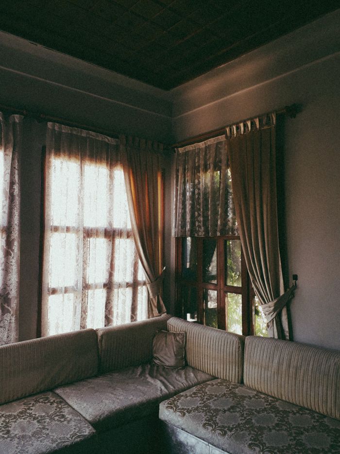 Warm and inviting living room interior with luxurious curtains and cushioned sofa.