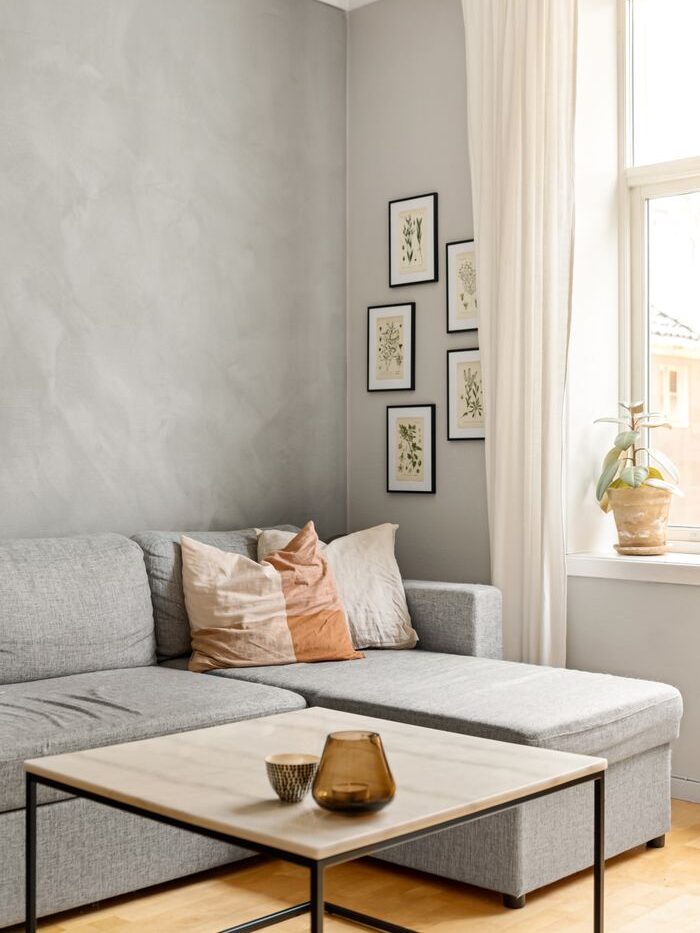 Chic minimalist living room featuring a grey sofa, modern art decor, and large window with natural light.