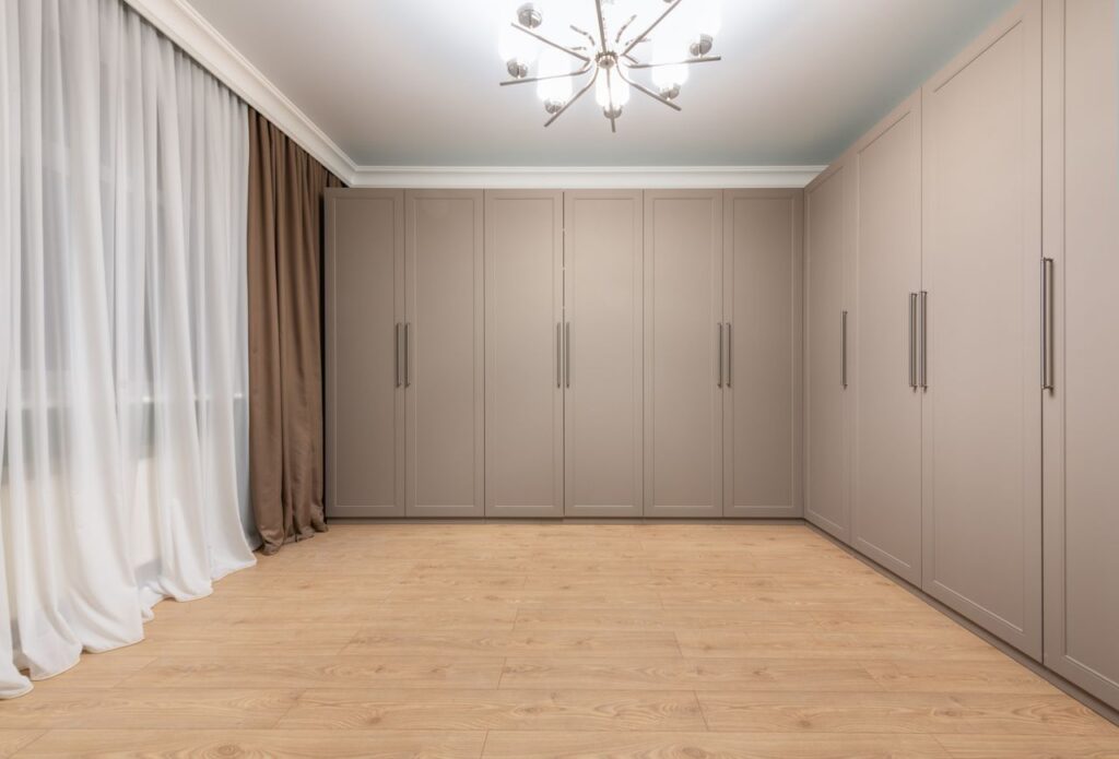 Curtains against modern closet on wooden floor under glowing lamp hanging on white ceiling in modern house room